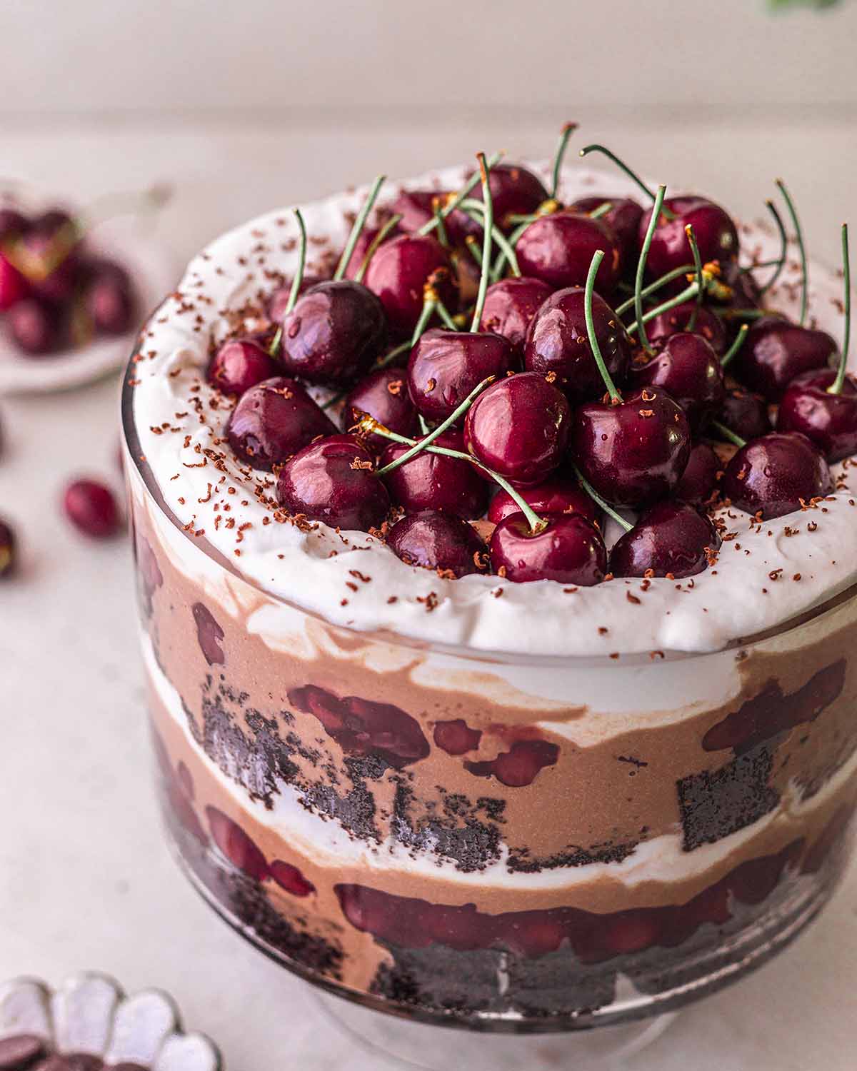 Close up of glistening fresh cherries on a bed of whipped coconut cream in trifle dish.