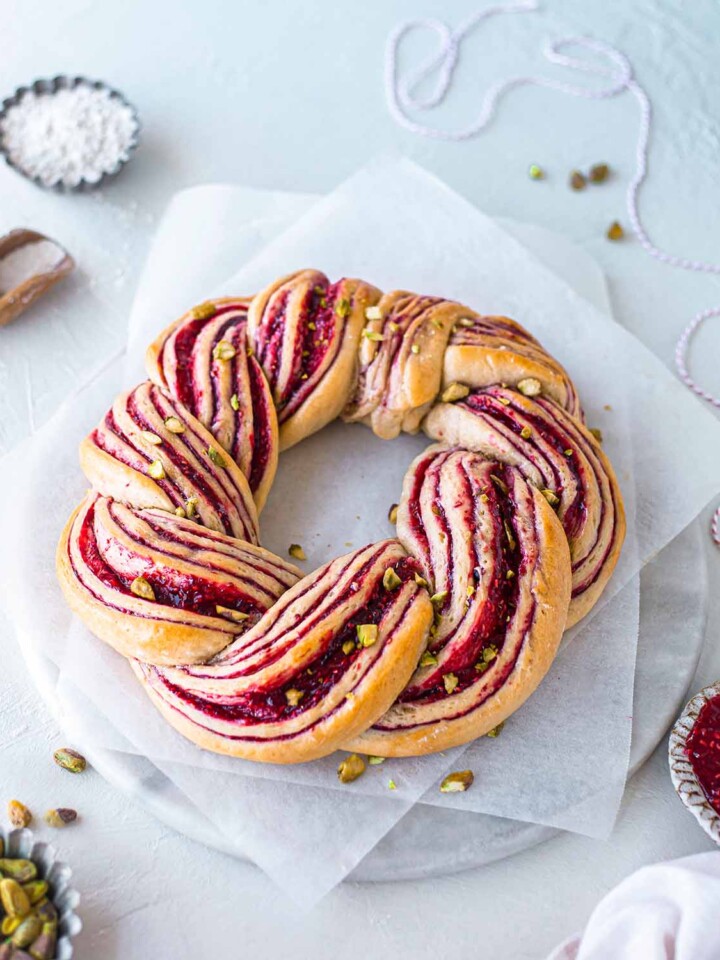 Raspberry and Pistachio Wreath on baking paper and marble serving board.