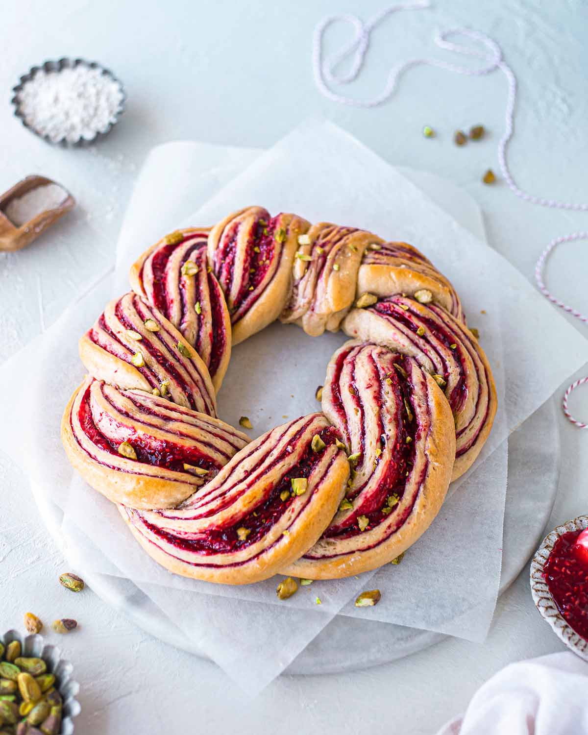 Raspberry and Pistachio Wreath on baking paper and marble serving board.