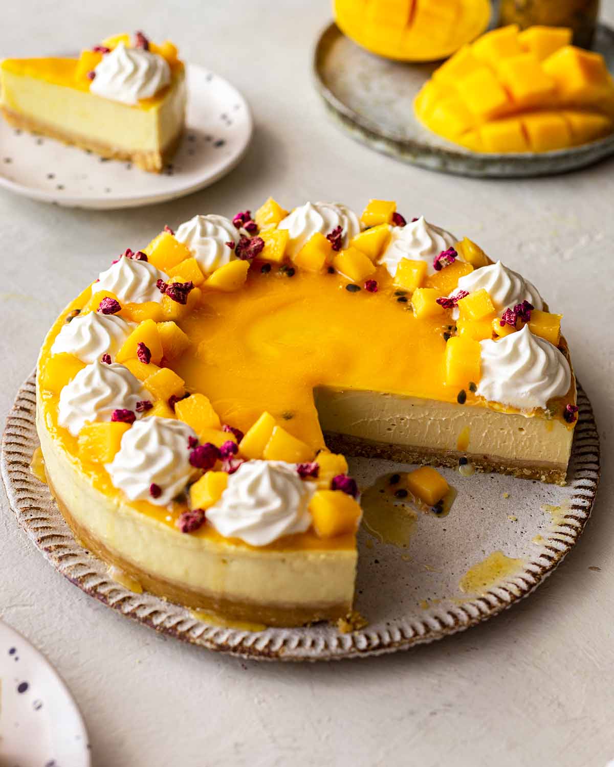 Golden vegan mango cheesecake on plate with slices cut out revealing creamy texture.