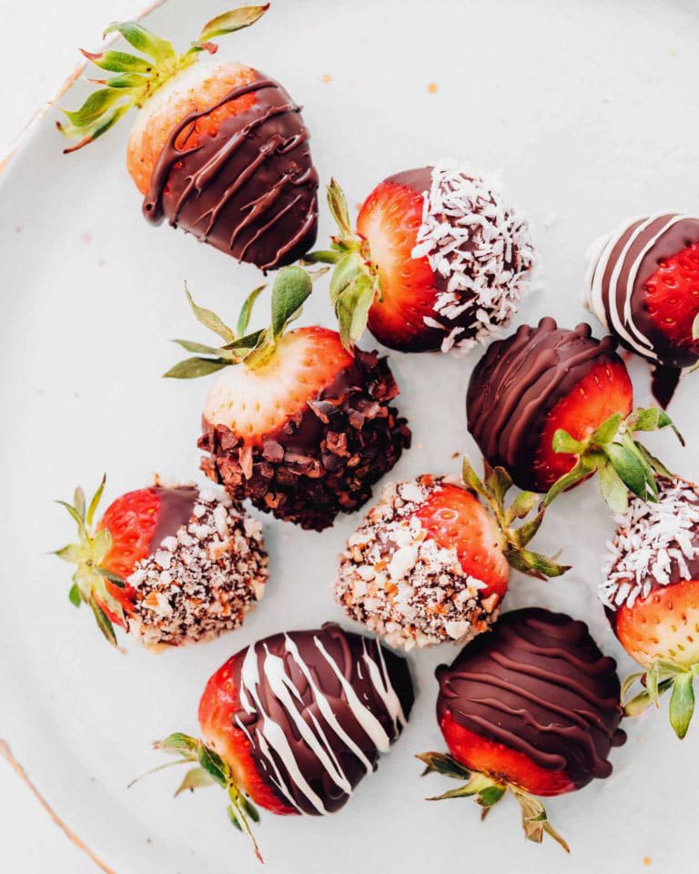 Close up of strawberries covered in chocolate, cocoa nibs, nuts and coconut.