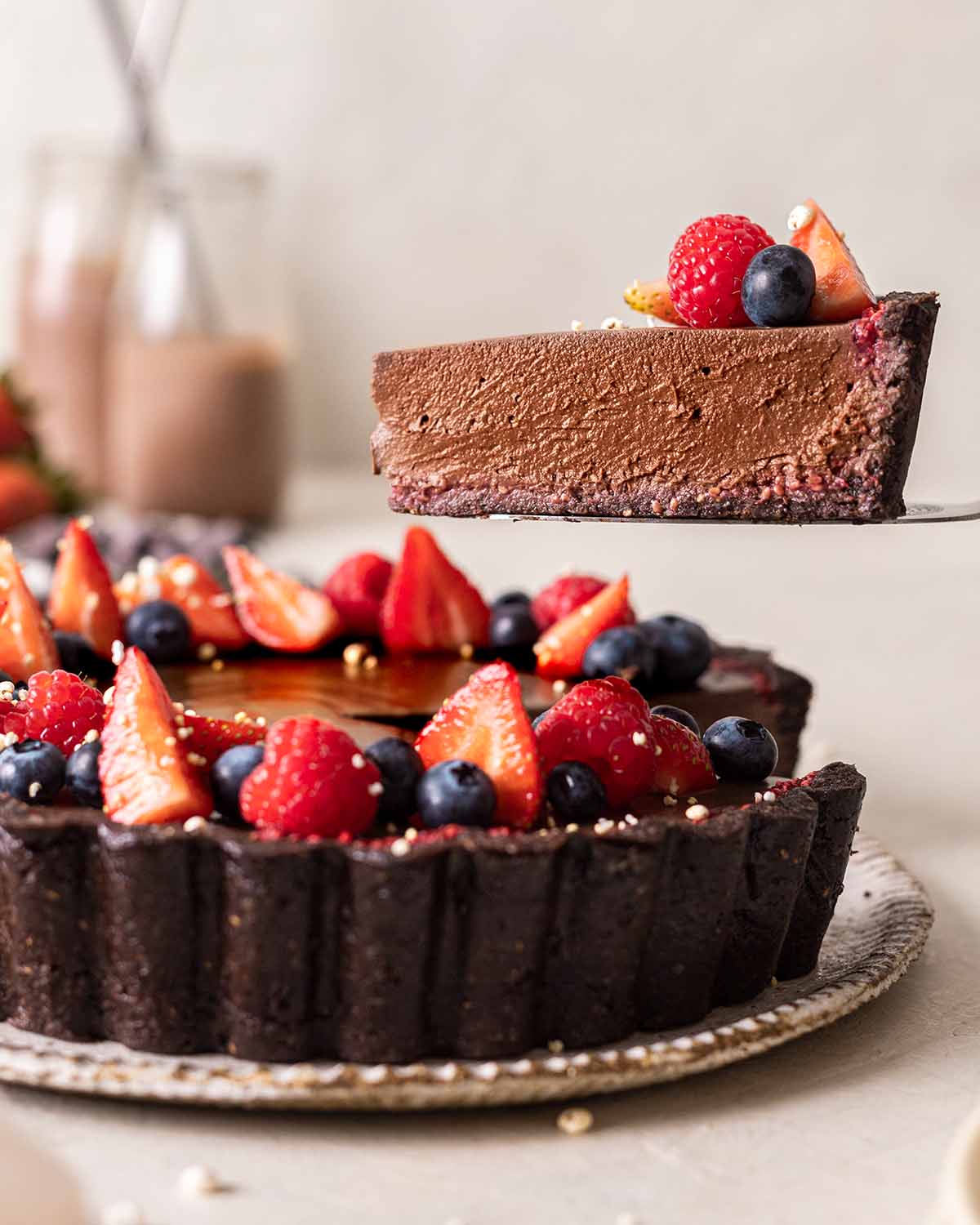 Slice of vegan chocolate tart lifted up  revealing the different layers and textures.