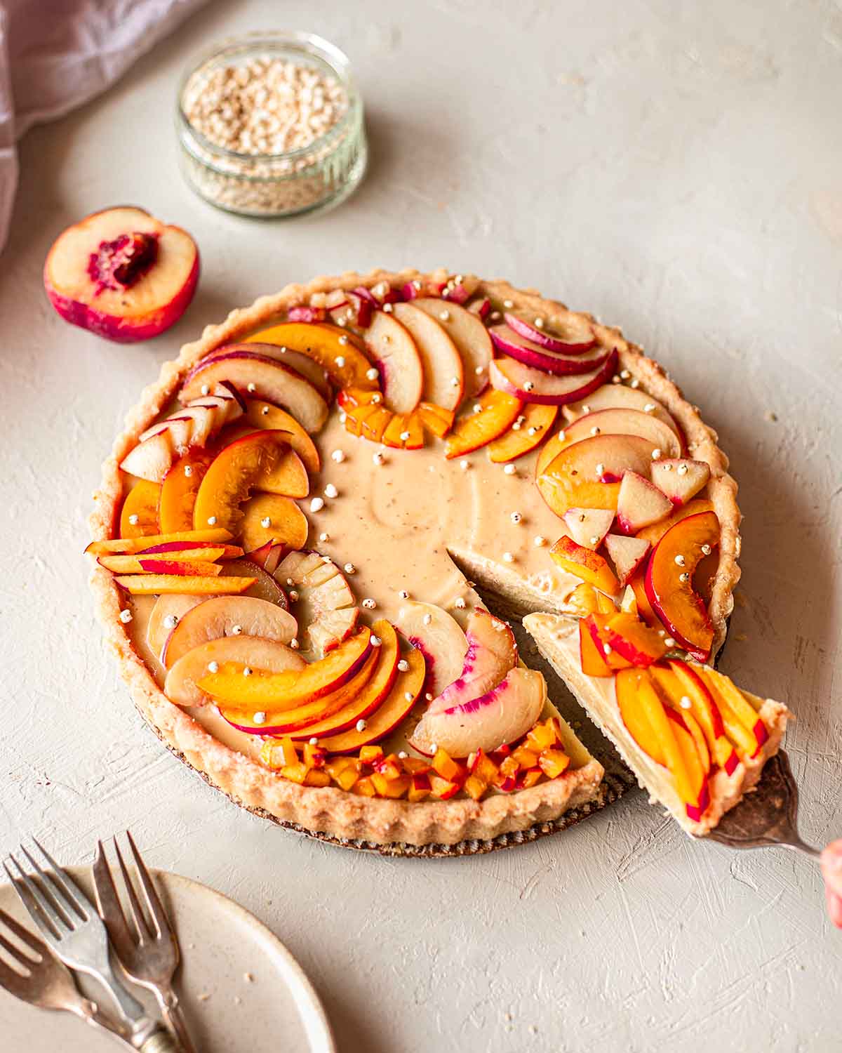 Vegan nectarine tart on plate with slice coming out.