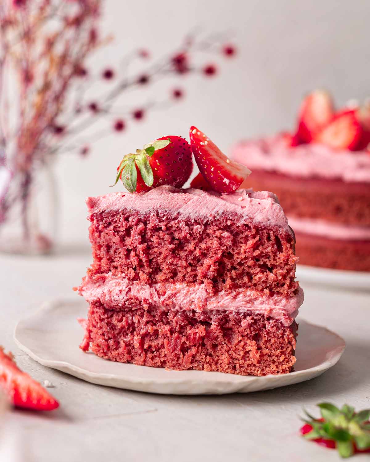 Individual slice of strawberry cake showing very fluffy and pink layers.