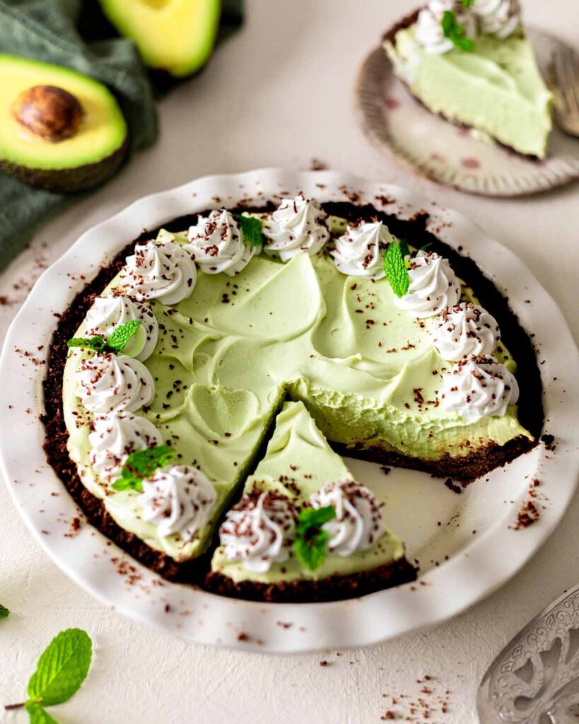 Side angle of grasshopper pie in pie dish. Slice is removed so you can see the creamy and fluffy texture of the mint filling.
