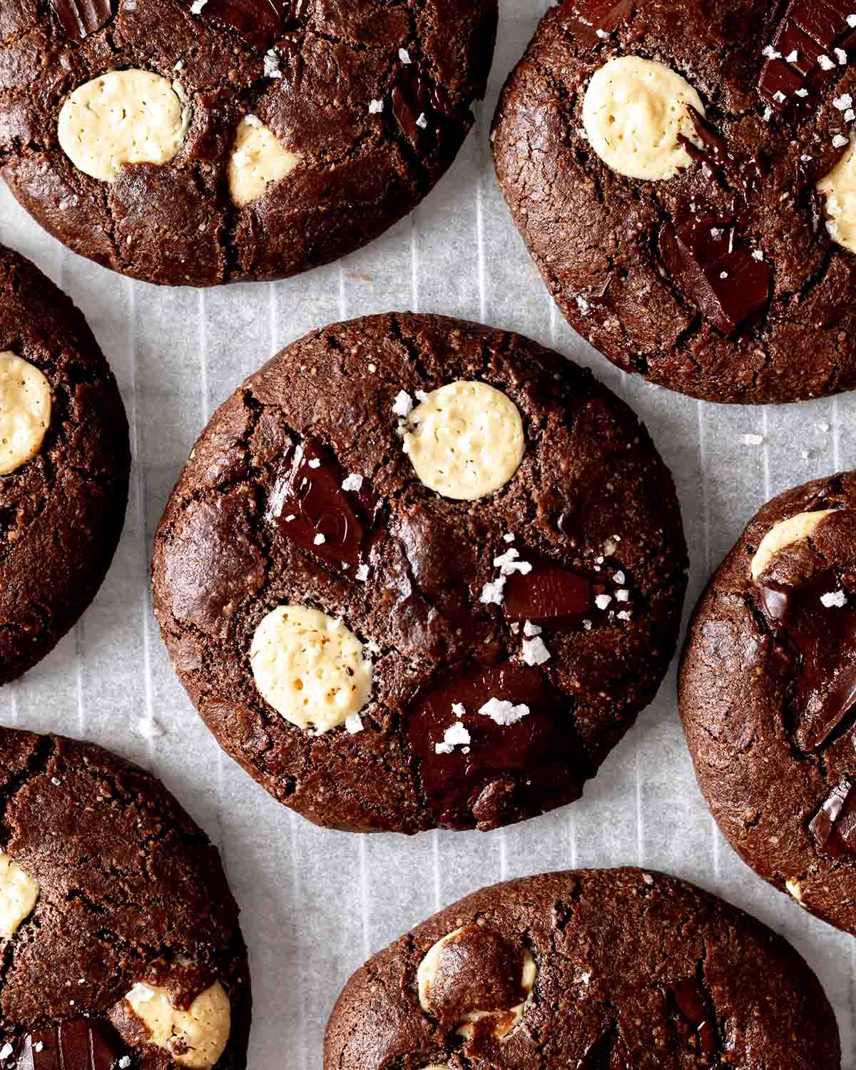 Close up of chocolate cookies with white chocolate chips and chunks of dark chocolate, sprinkled with coarse salt.