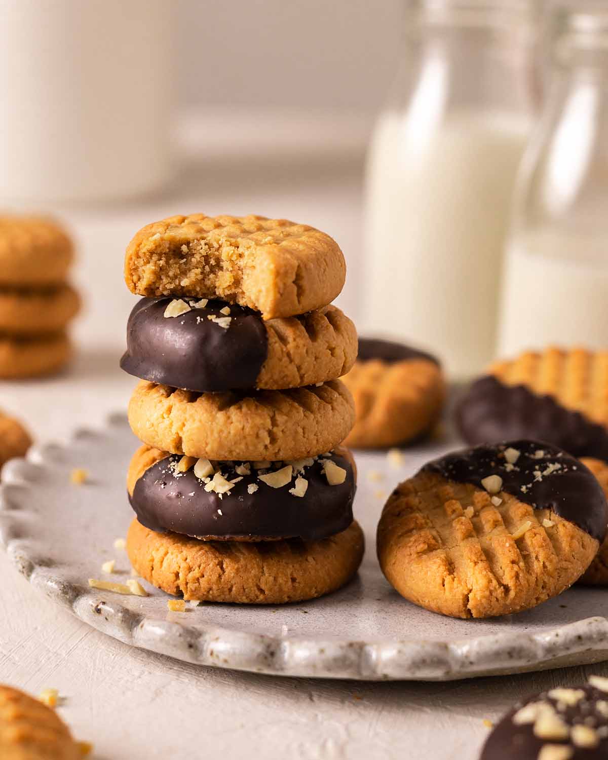Stack of peanut butter cookies with bite taken out of one cookie revealing texture.