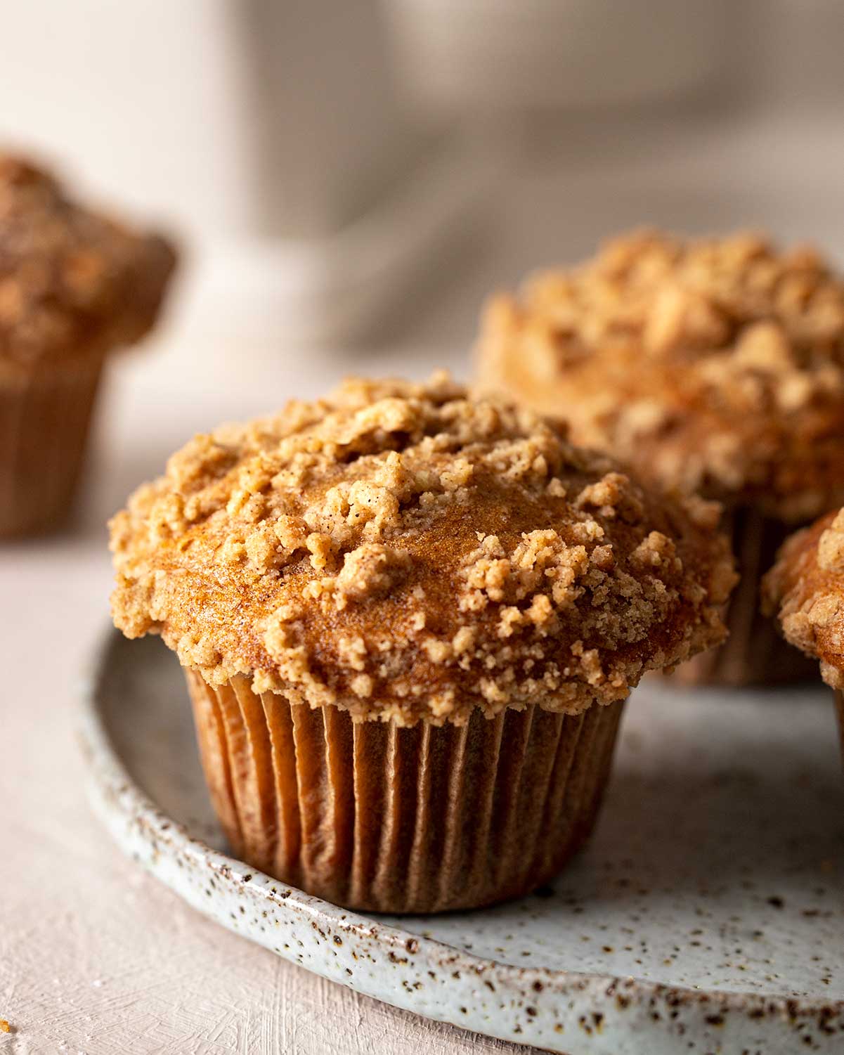 Close up of golden vegan banana muffin with a very large muffin top and crumb topping.