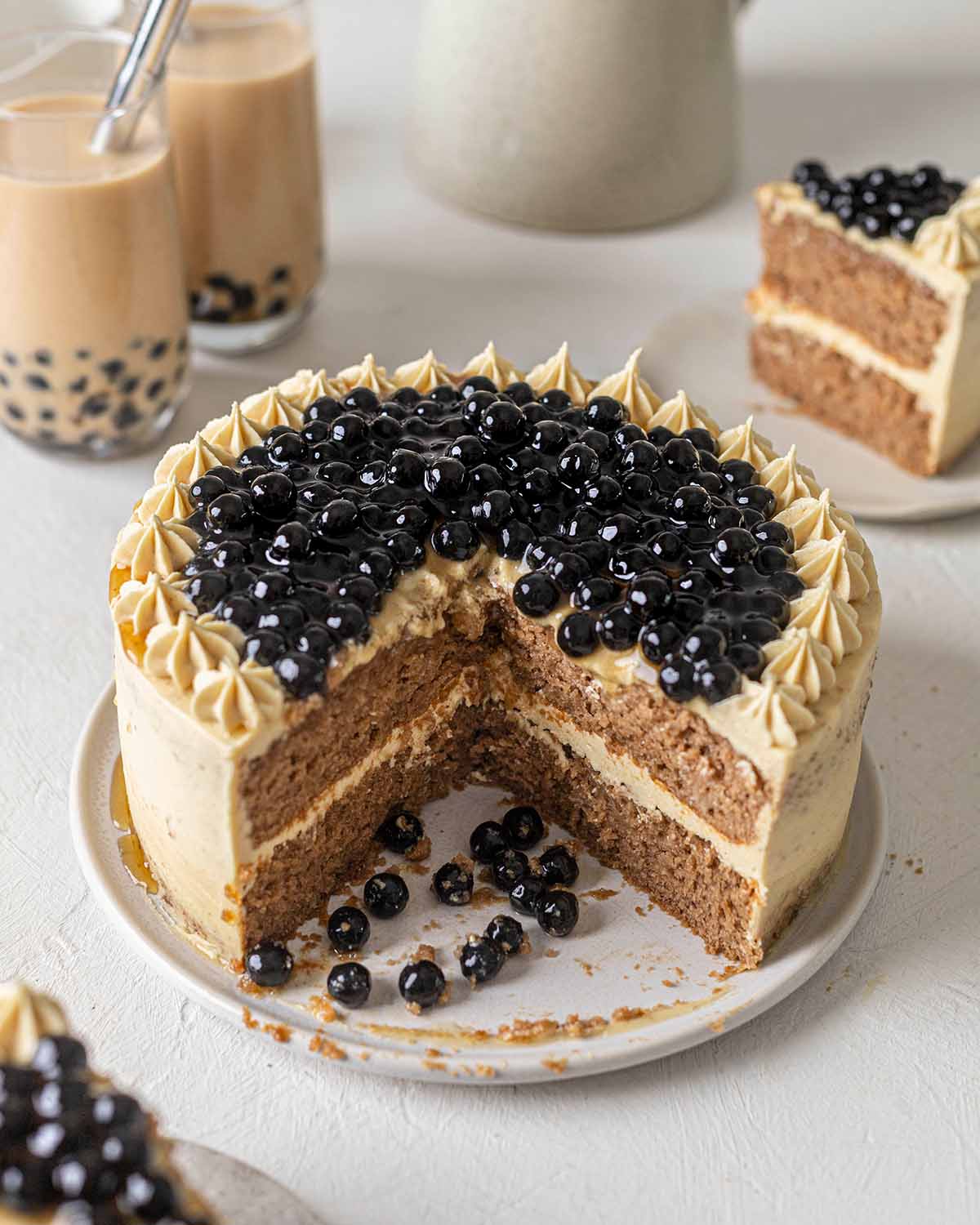 Two-layered vegan boba cake cut open showing sponge layers. Cake is topped with shiny tapioca pearls.