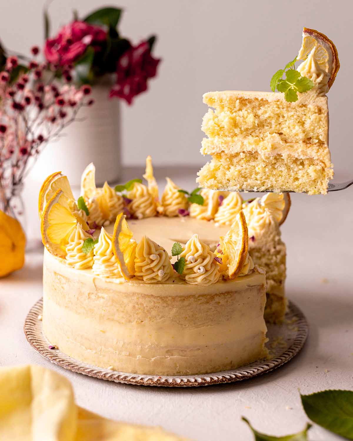 Stylized lemon cake with slice lifted up showing two fluffy cake layers.
