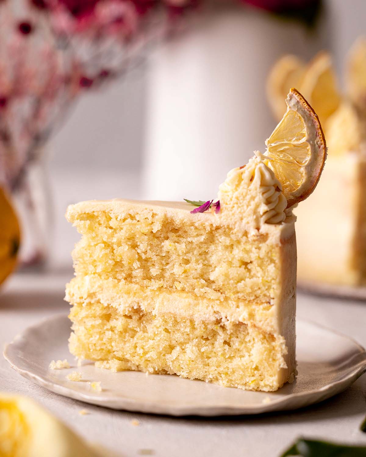 Close up of one tall slice of lemon cake on plate.