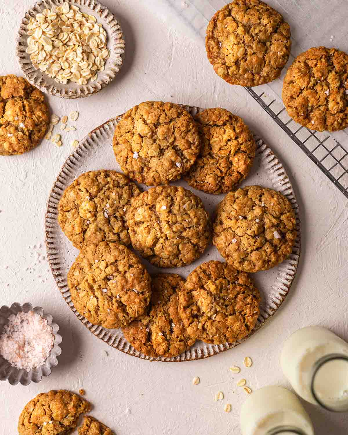 Overhead image of oatmeal cookies on rustic plate with ingredients surrounding the plate.