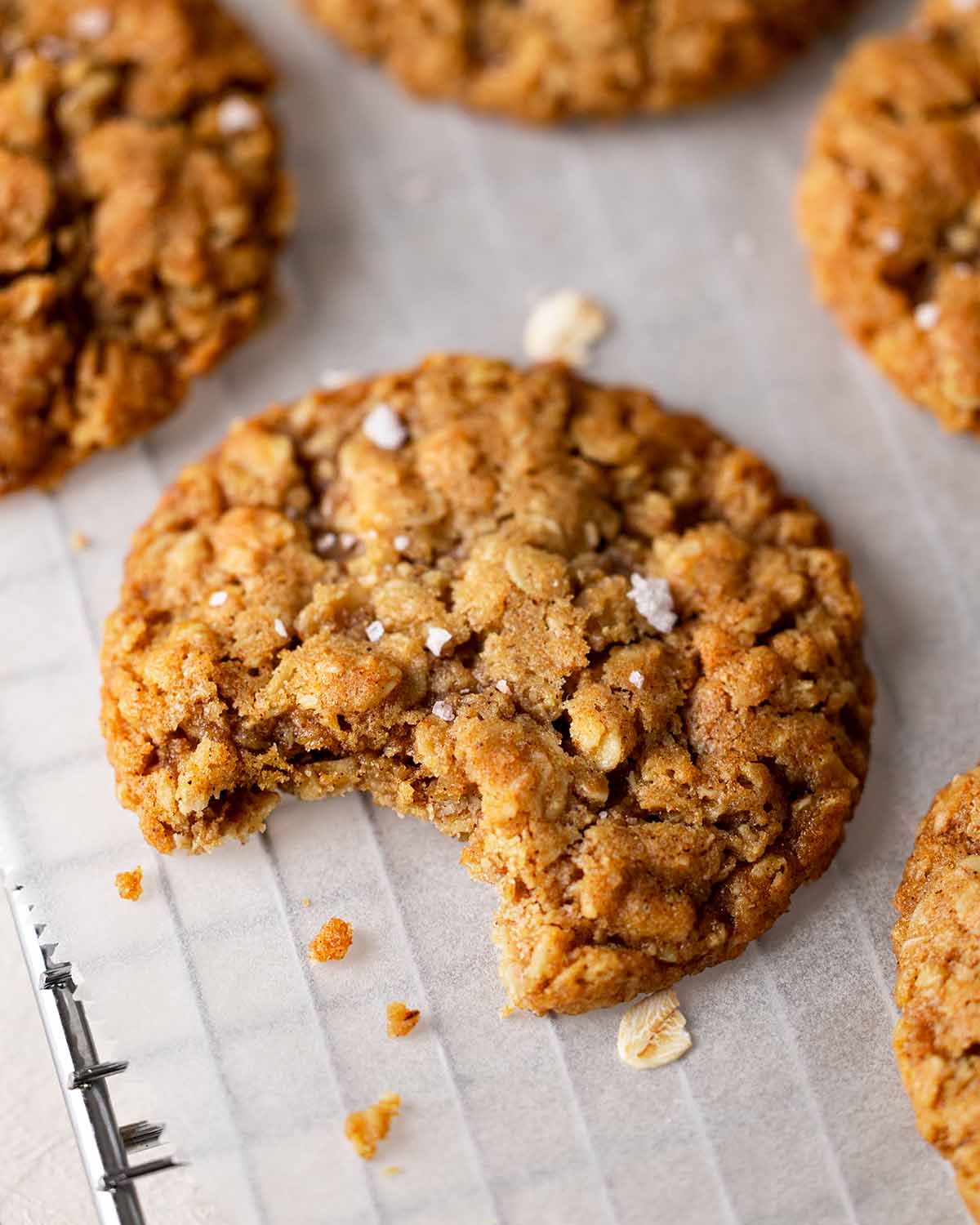 Close up of one oatmeal cookie with bite taken out revealing soft chewy texture.