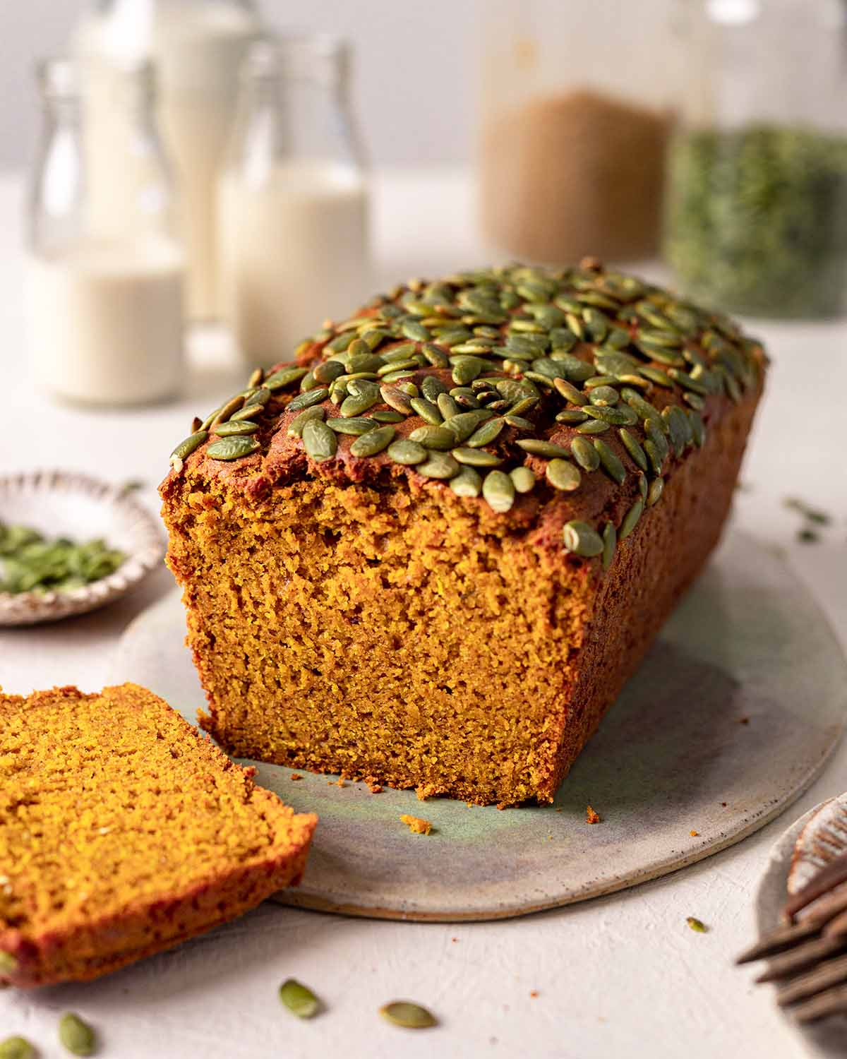 Loaf of pumpkin bread on plate with slice cut off showing texture of the bread.