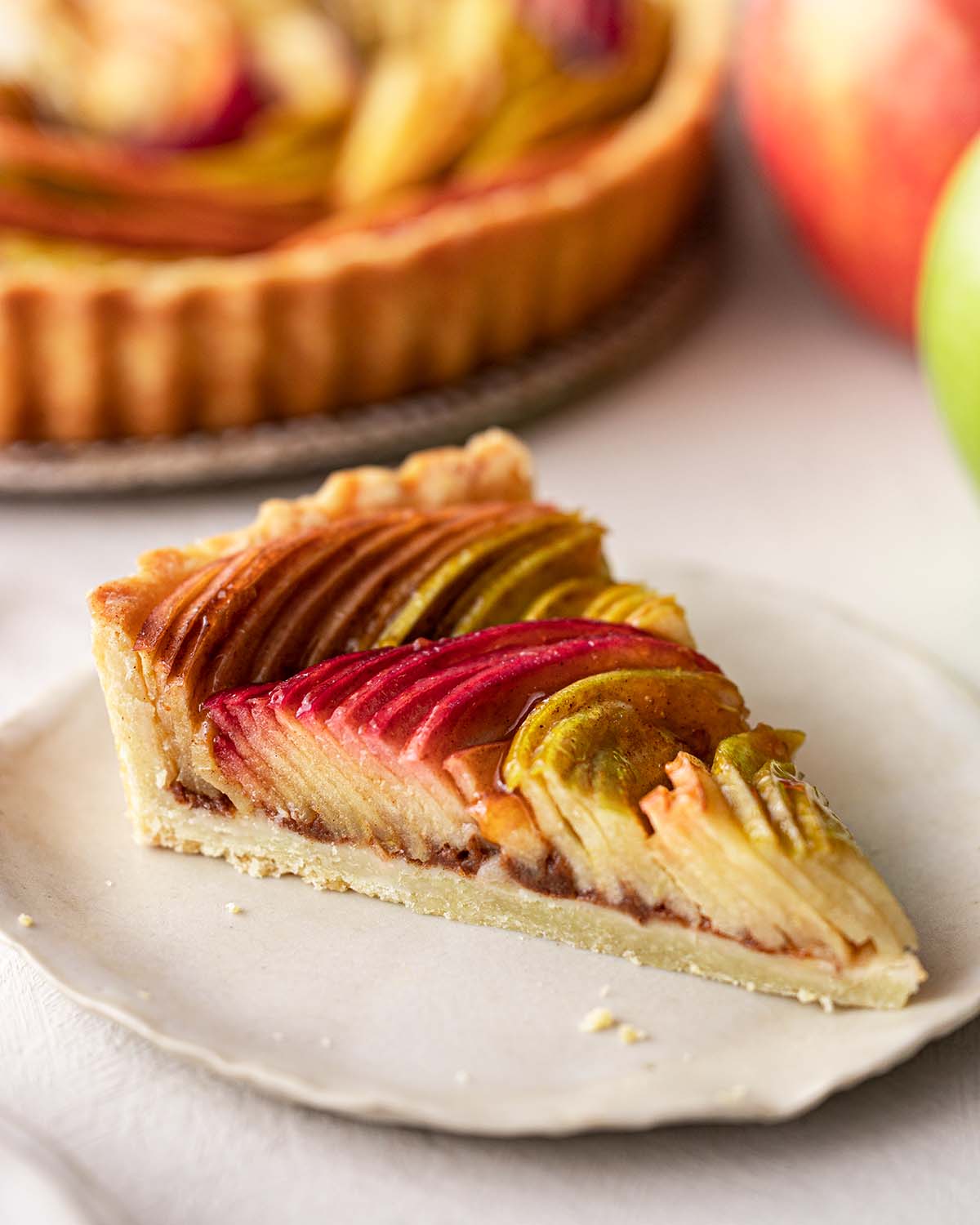 Individual slice of apple tart revealing layers of apple slices.