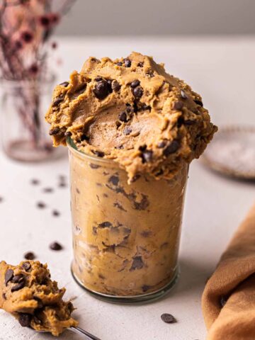 Chickpea cookie dough in a glass jar showing fudgy and messy texture.