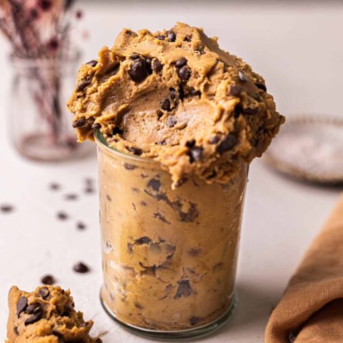 Chickpea cookie dough in a glass jar showing fudgy and messy texture.