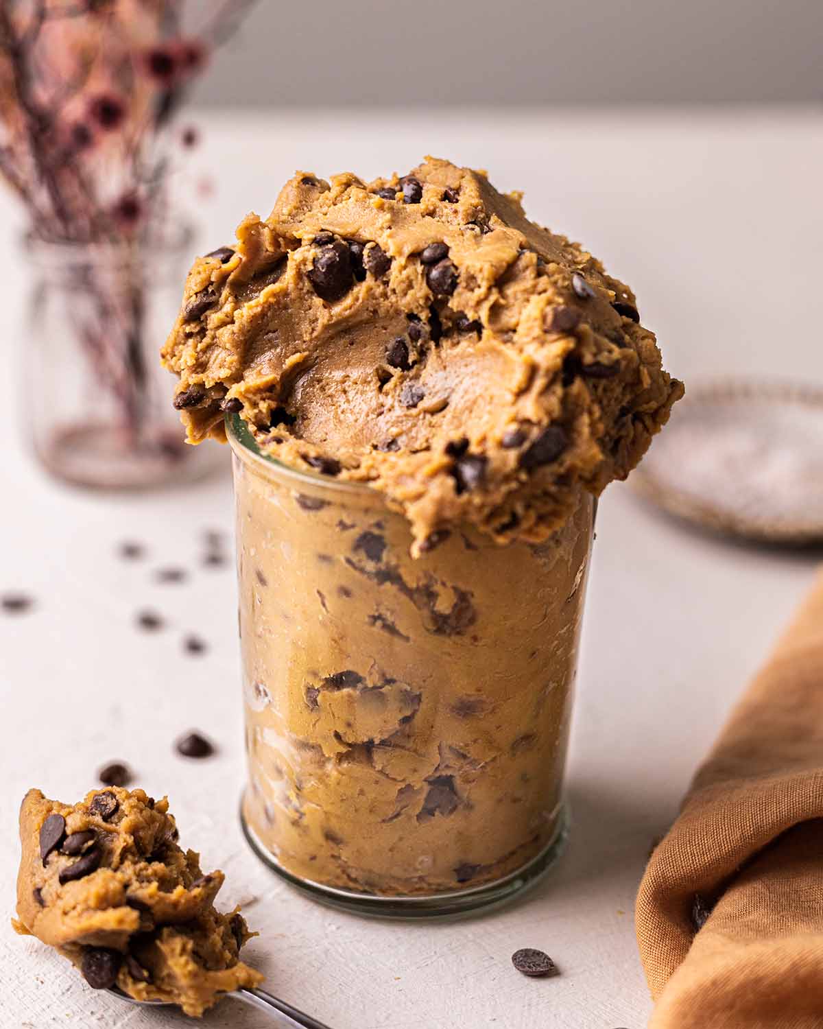 Fudgy chickpea cookie dough in a glass jar with scoop taken out.