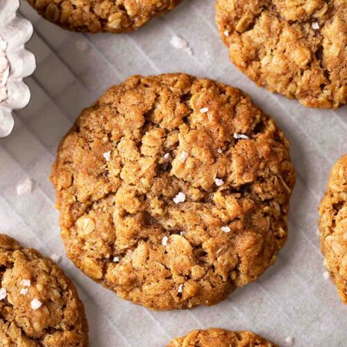 Close up of vegan oatmeal cookies with sprinkle of flaked salt on parchment paper.