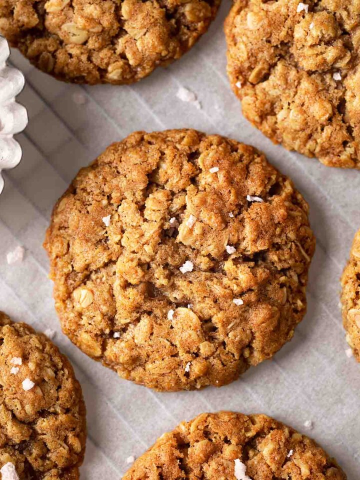 Close up of vegan oatmeal cookies with sprinkle of flaked salt on parchment paper.