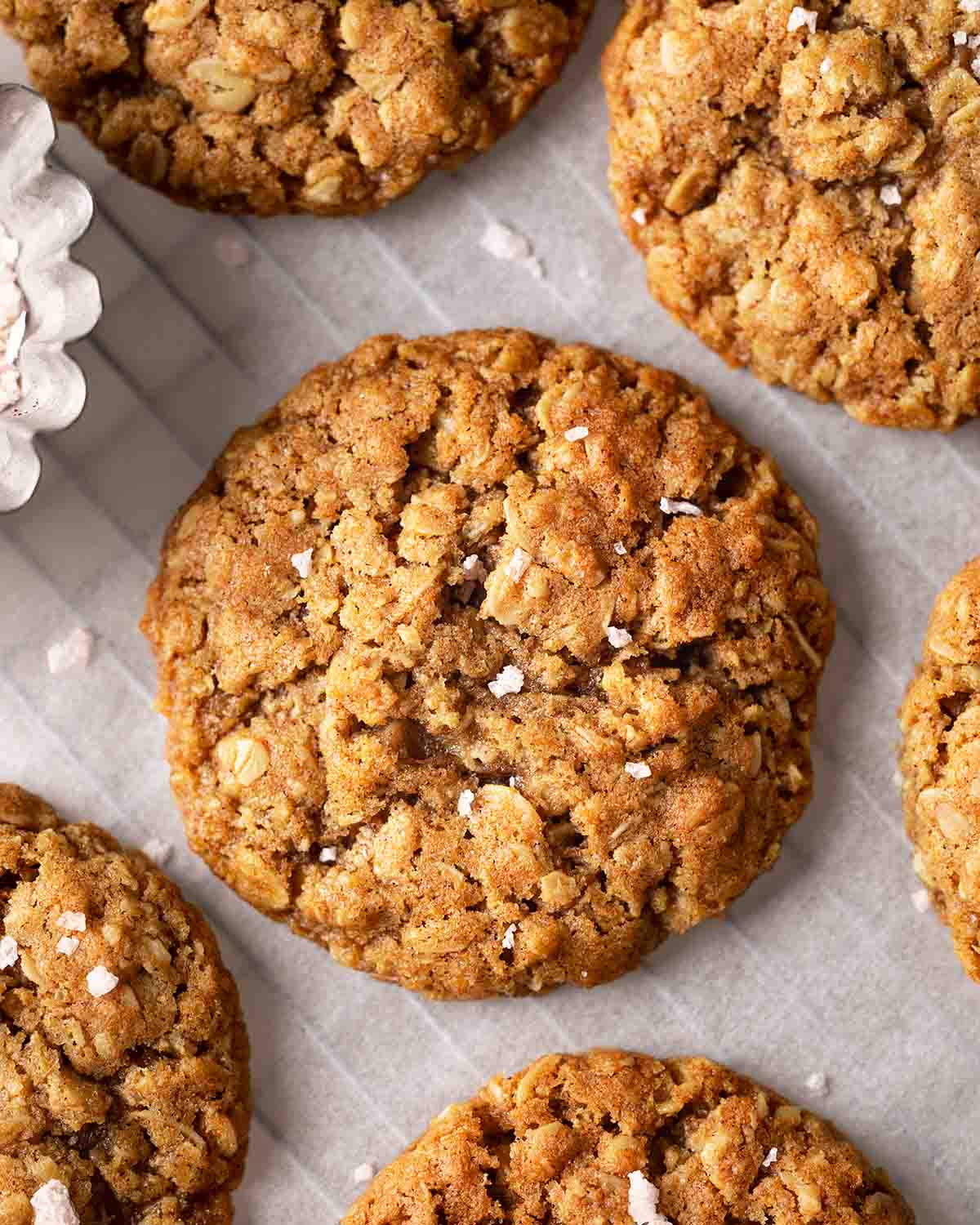 Close up of vegan oatmeal cookies with sprinkle of flaked salt on parchment paper.