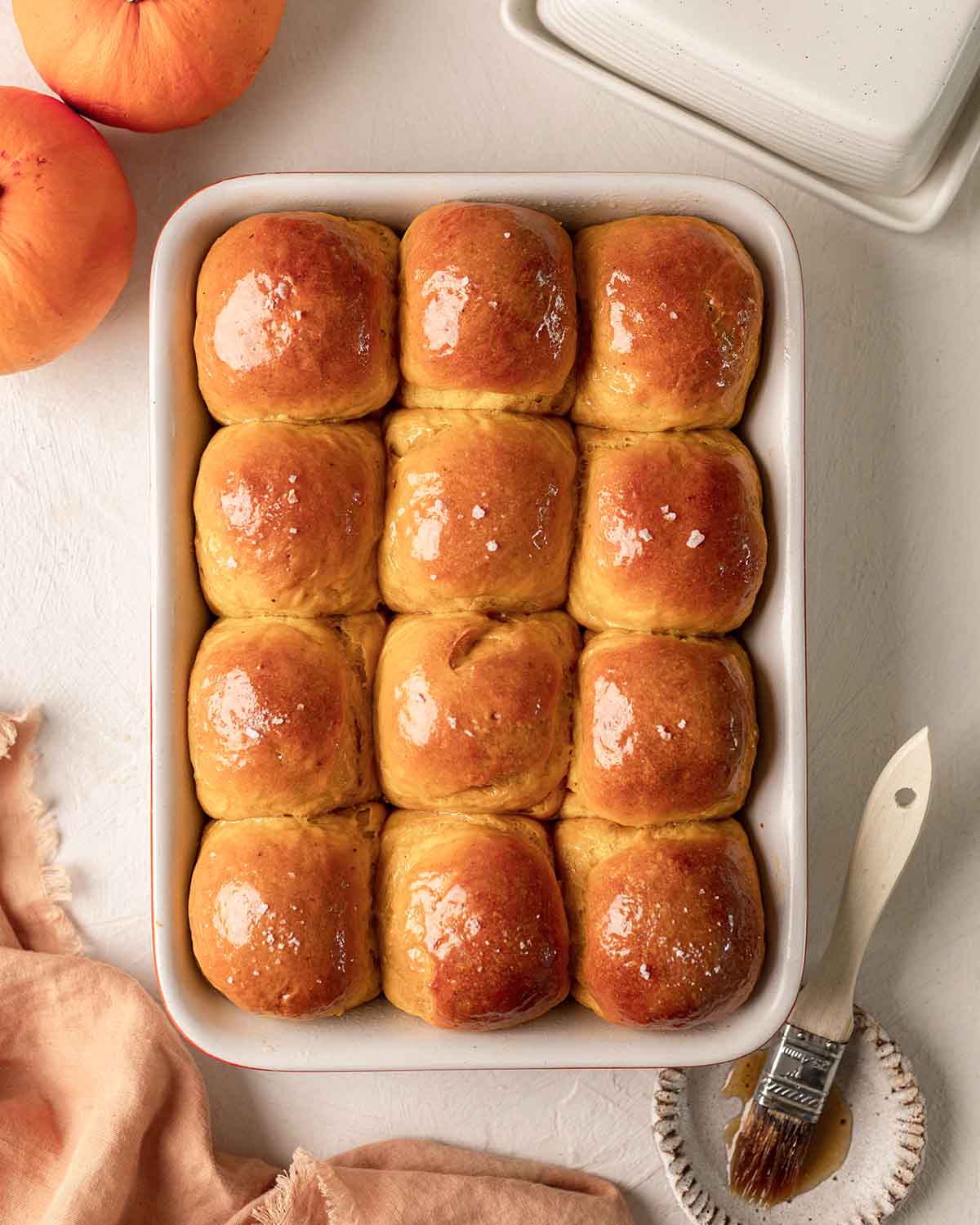 Dozen of golden pumpkin buns in baking tray.