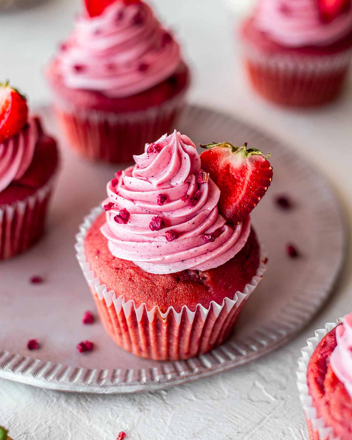 Close up of pink cupcake focusing on pastel pink strawberry frosting.