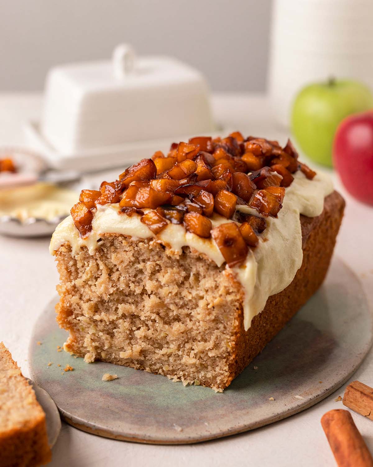 Vegan apple bread topped with cream cheese frosting and caramelized apples.