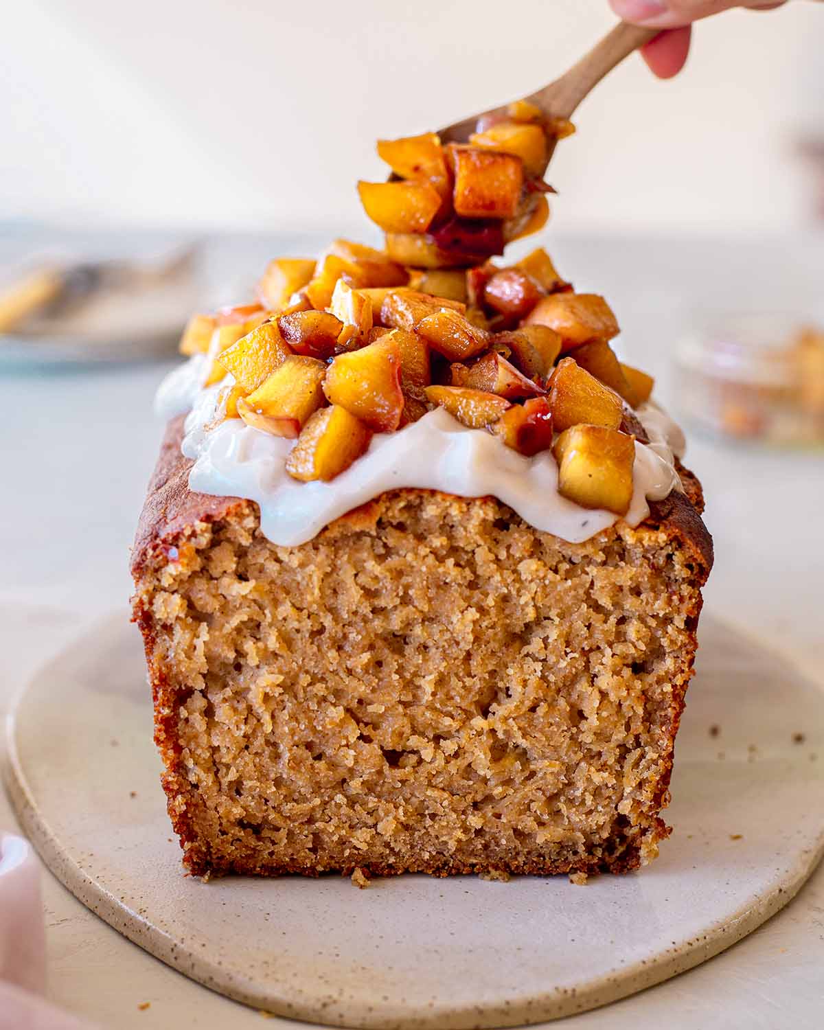 Gluten free vegan apple bread topped with coconut yogurt. Spoon is topping bread with caramelized apples.