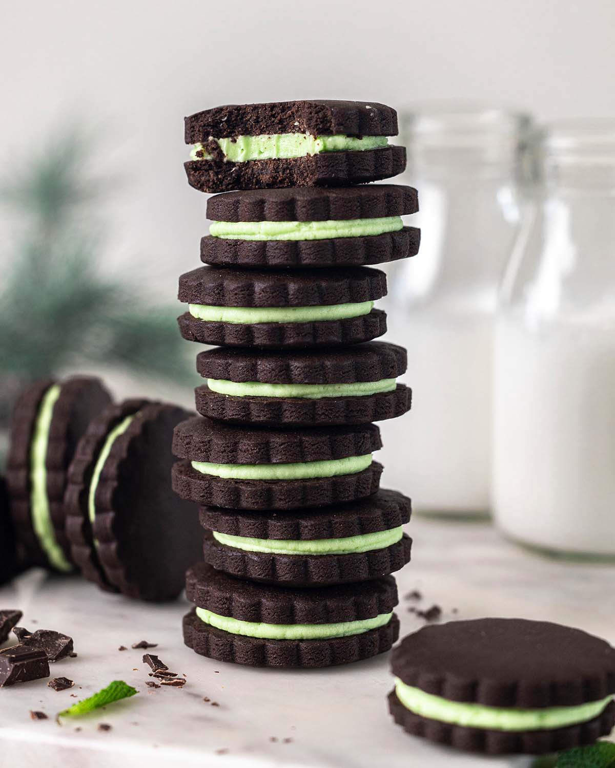 Tall stack of vegan mint chocolate cookies with pastel green cream filling.