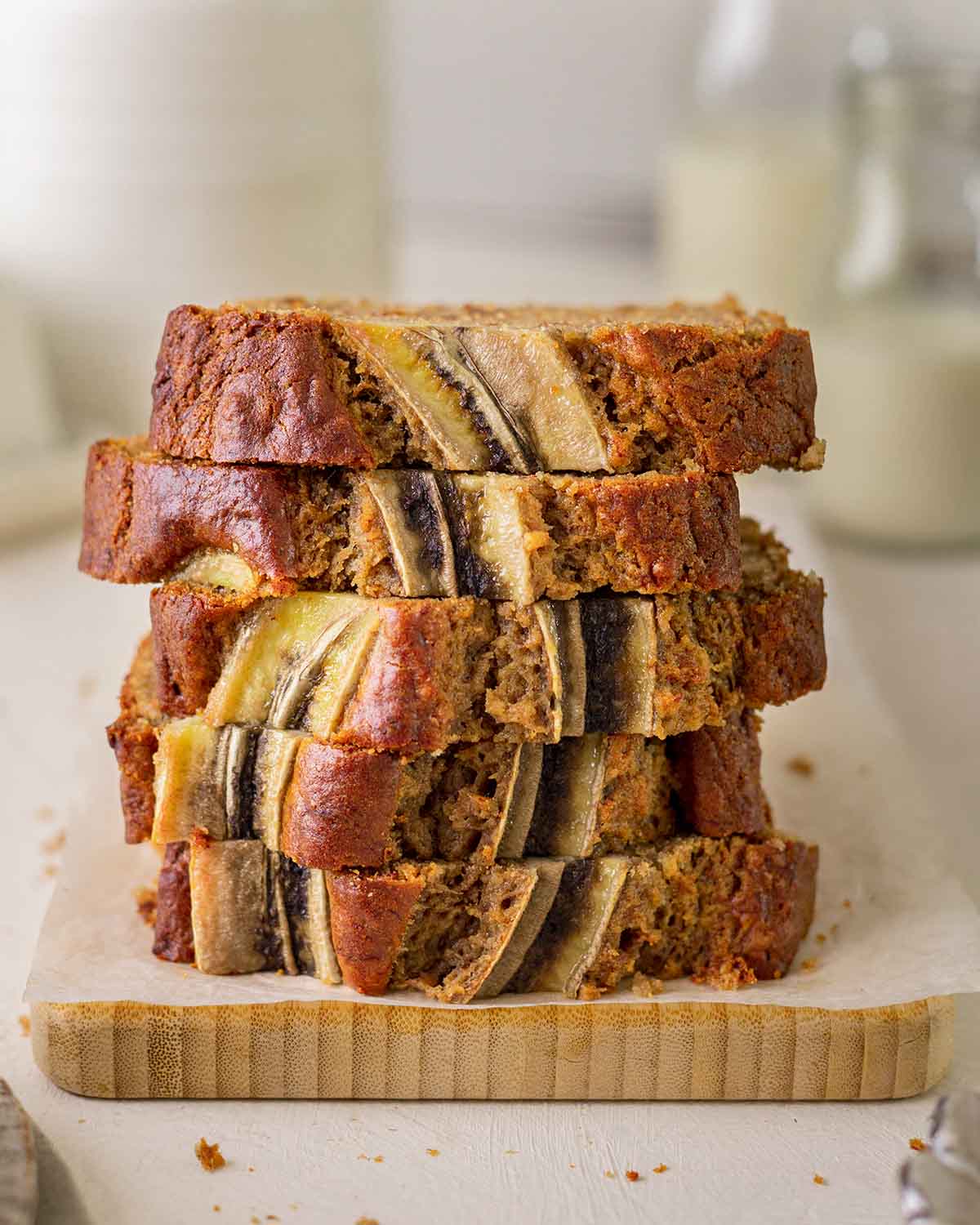 Stack of slices of banana bread showing golden top and caramelized banana on top.