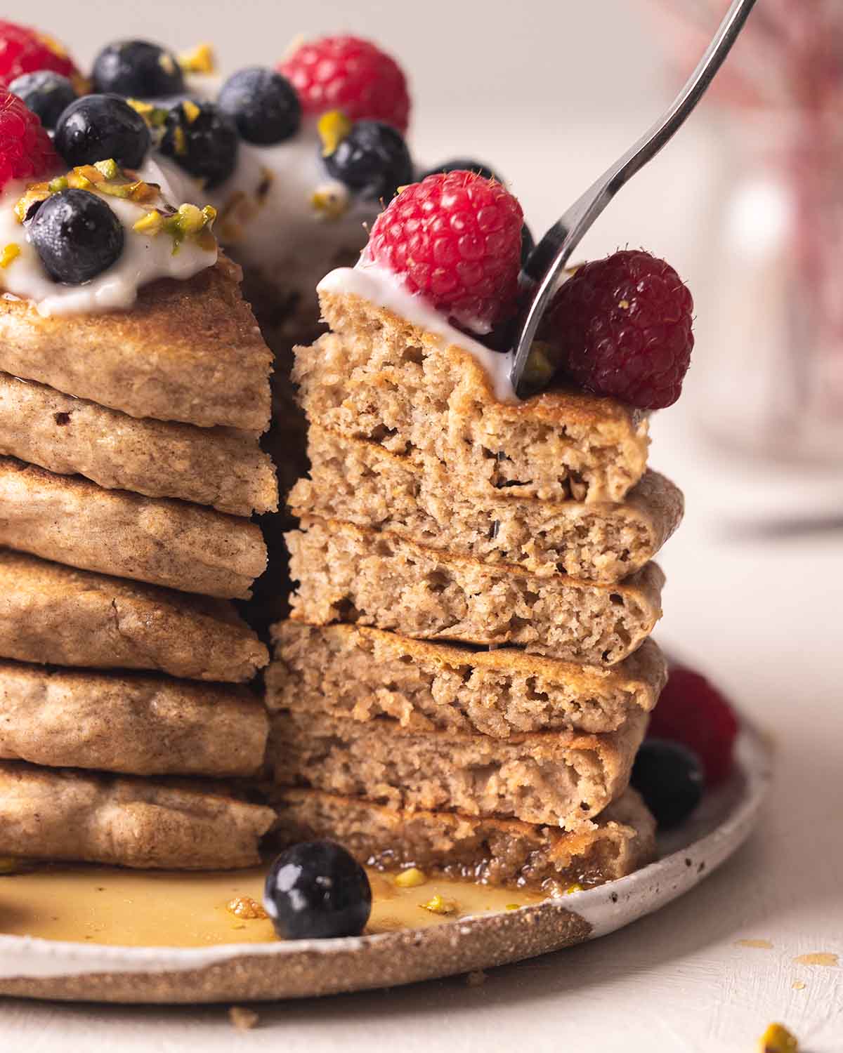 Close up of pancakes stack with fork taking out a slice revealing the fluffy texture.