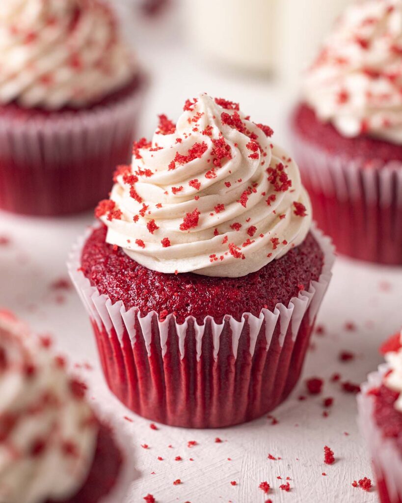 Close up of vegan red velvet cupcake with generous cream cheese frosting 