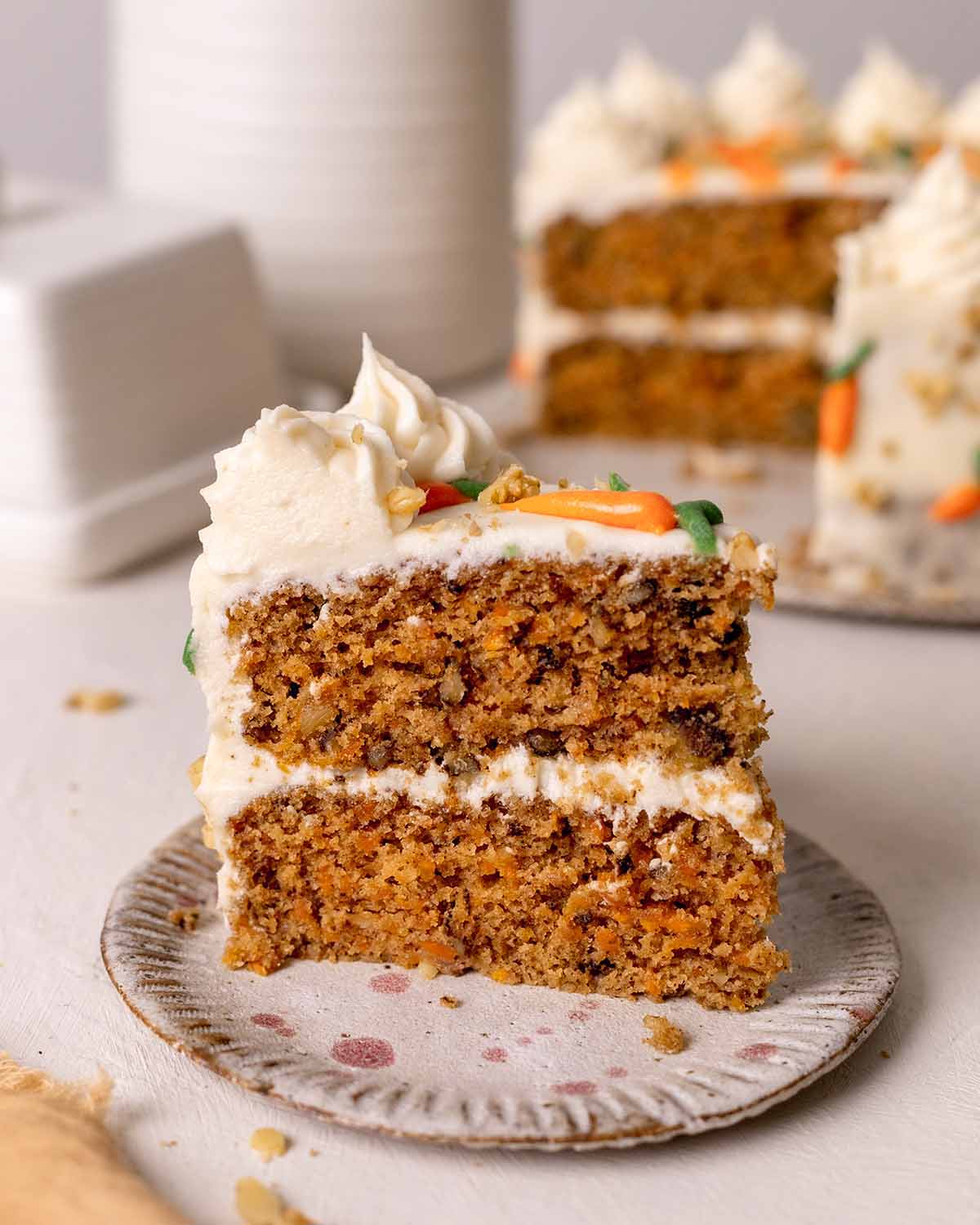 Close up of one slice of carrot cake showing layers, golden interior and coarse texture.