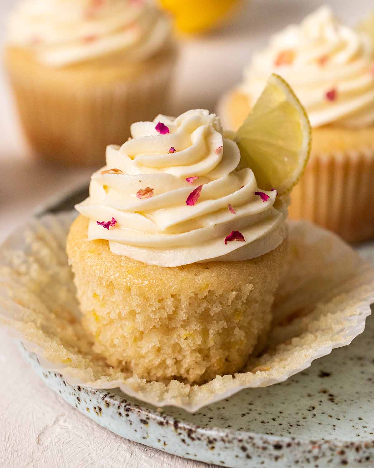 Close up of lemon cupcake with cupcake liner pulled off showing fluffy interior.