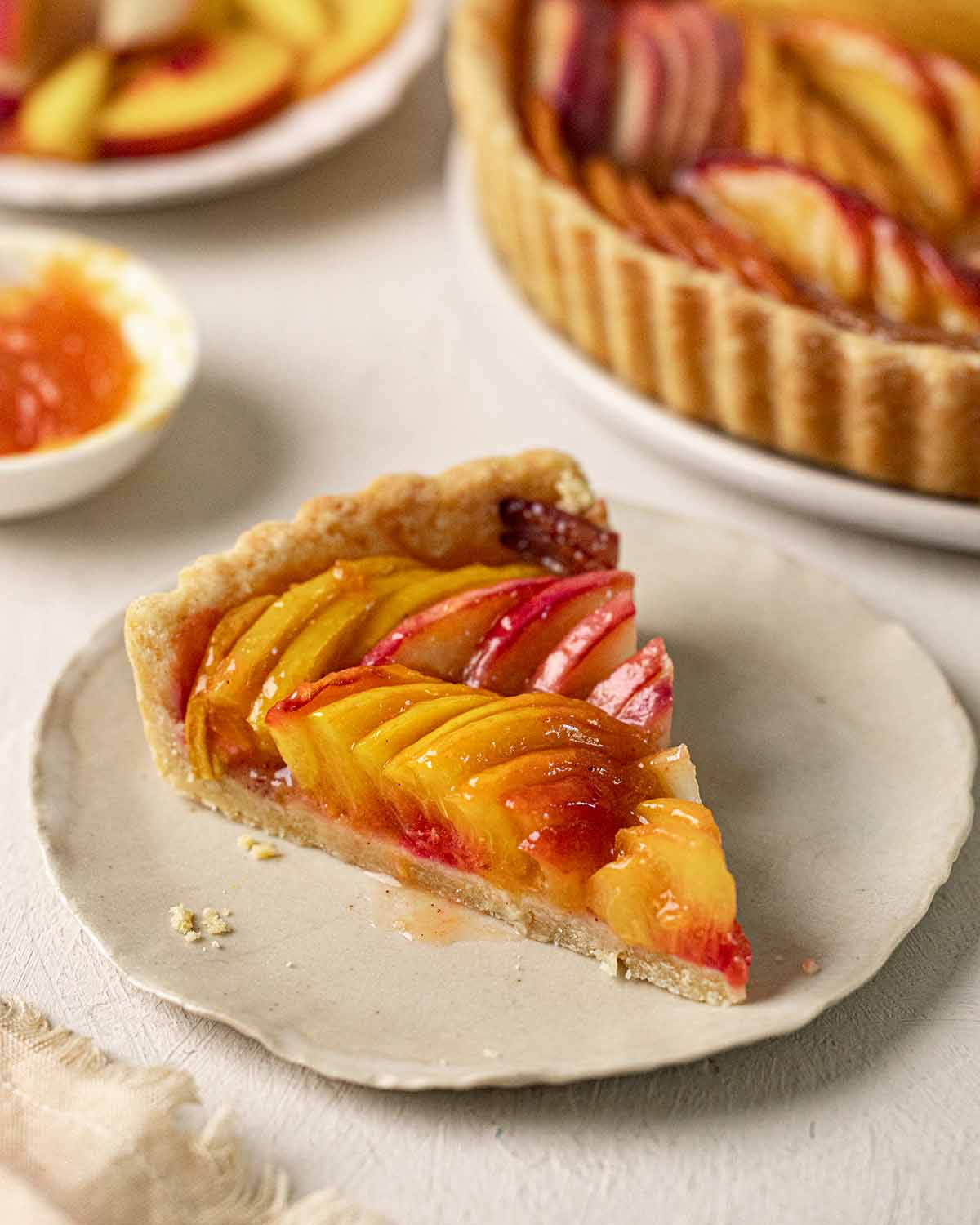 Close up of a slice of the baked peach tart on a plate.