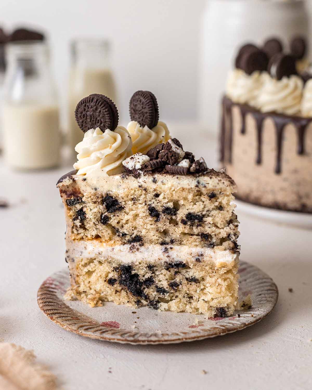 Close up of slice of vegan oreo cake showing fluffy texture and large chunks of cookies in cake.
