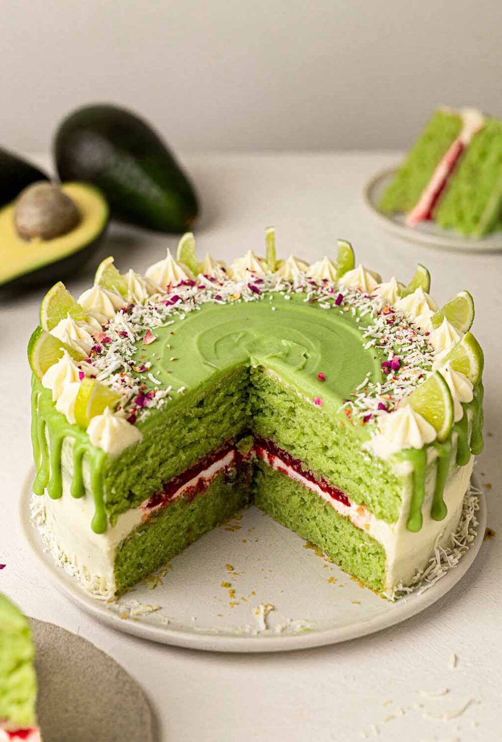 Cross section of light green colored cake with raspberry jam in middle. Cake is covered in green and white icing.