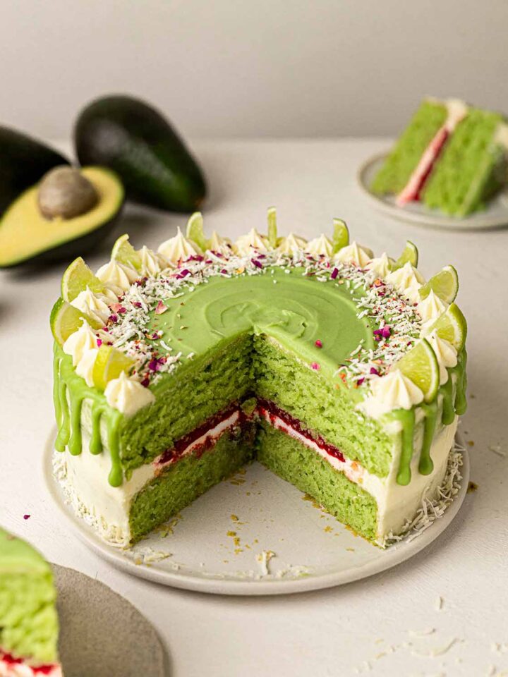 Cross section of light green colored cake with raspberry jam in middle. Cake is covered in green and white icing.