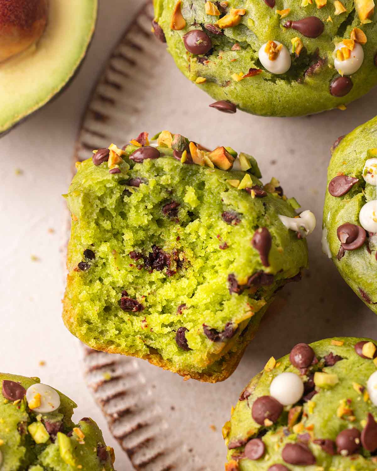 Close up of avocado muffin which has a bite taken out, revealing fluffy green interior.
