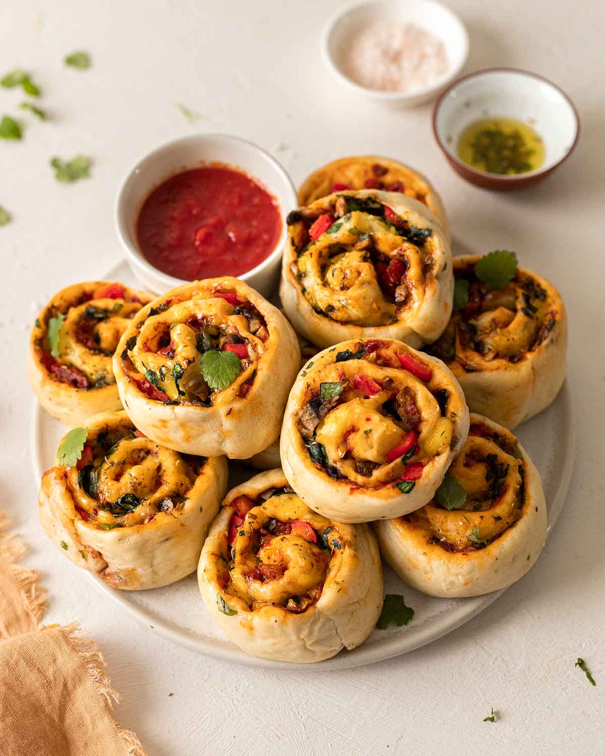 Vegan pizza rolls on plate with small dish of marinara sauce.