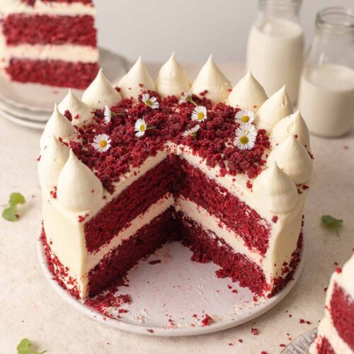 Vegan red velvet cake on plate with slices cut open showing cross section of cake.