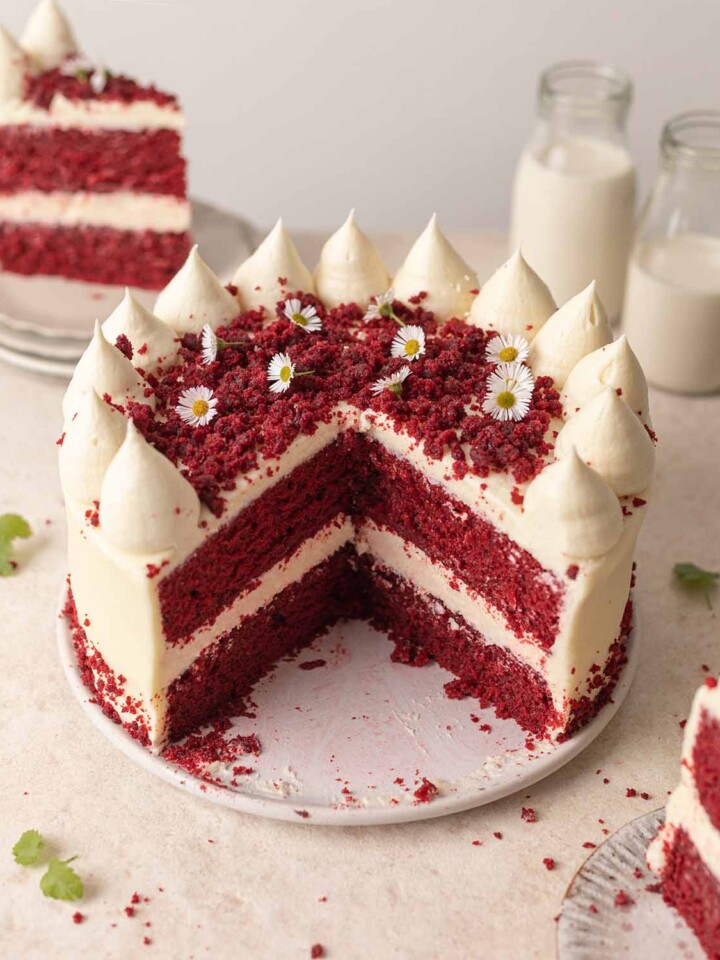 Vegan red velvet cake on plate with slices cut open showing cross section of cake.
