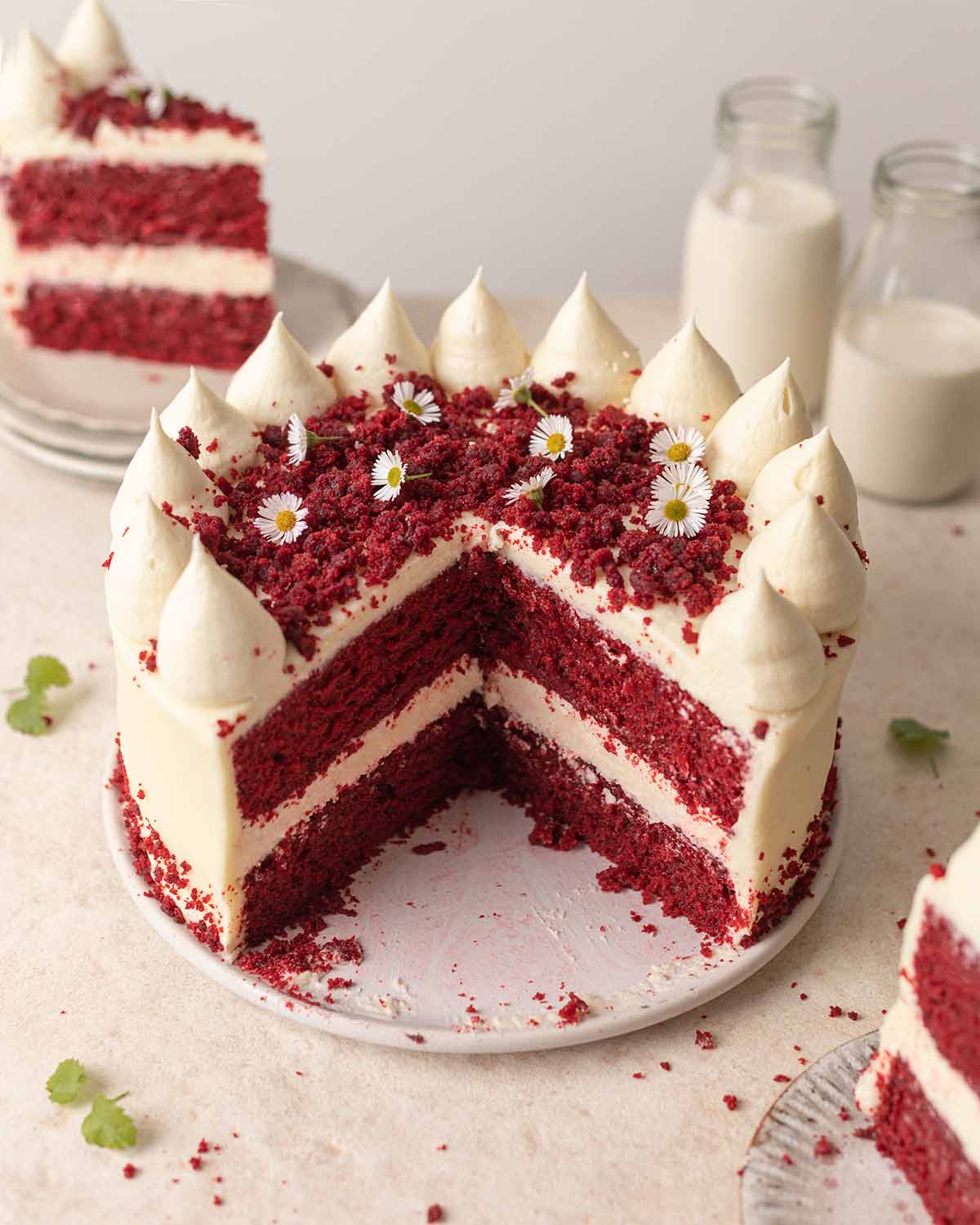 Vegan red velvet cake on plate with slices cut open showing cross section of cake.