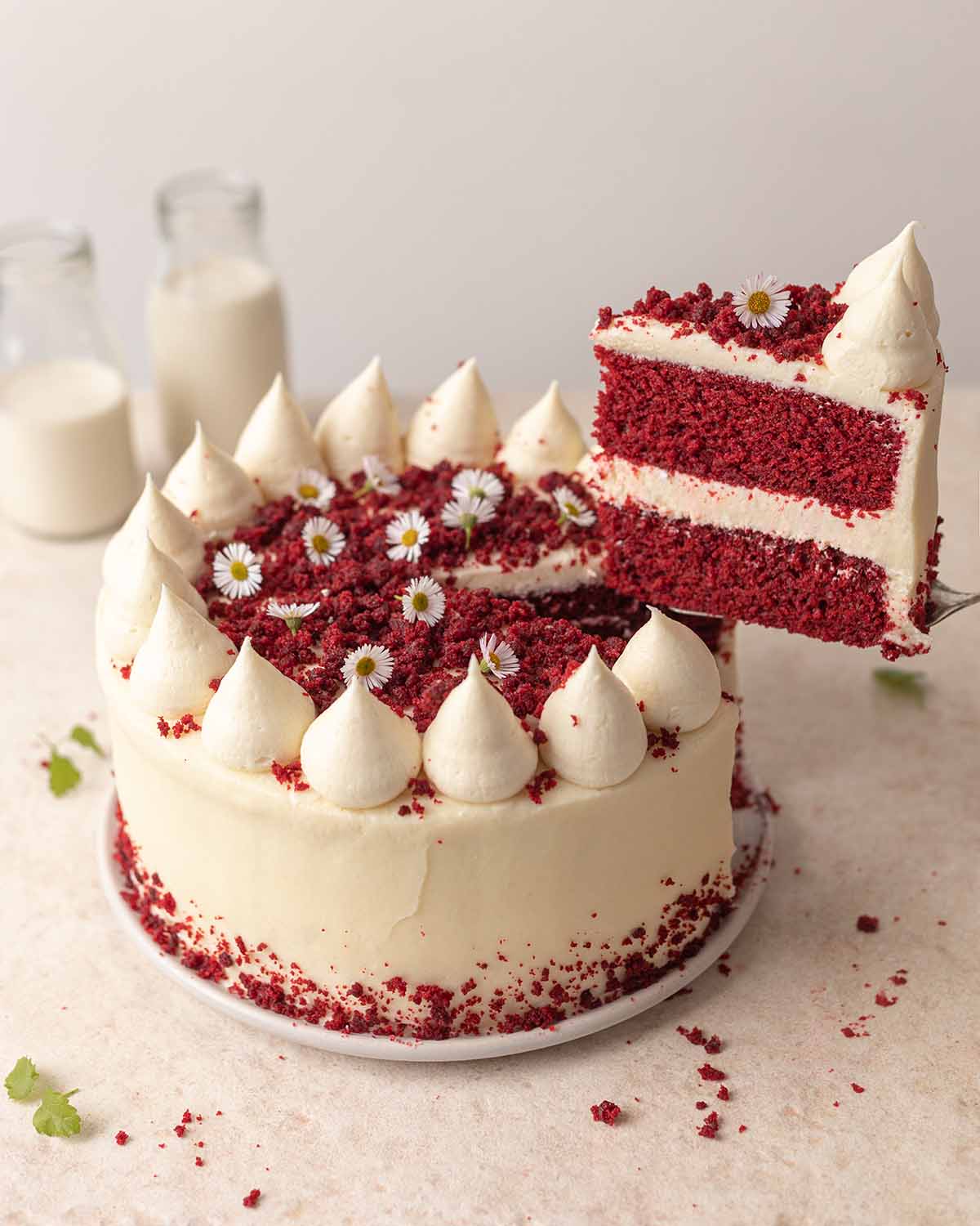 Red velvet cake on plate with slice cut out lifted up revealing layers.