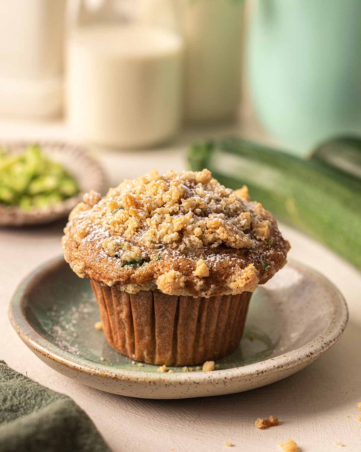 Vegan zucchini muffin with large muffin top and lightly dusted with powdered sugar.