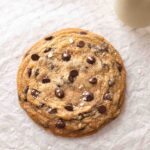 Large vegan chocolate chip cookie on parchment paper.