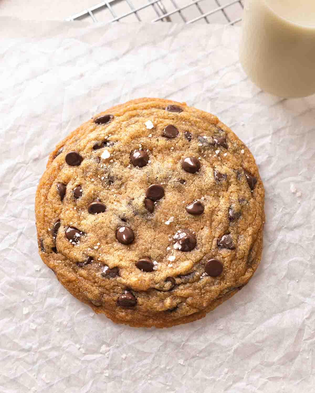 Large vegan chocolate chip cookie on parchment paper.