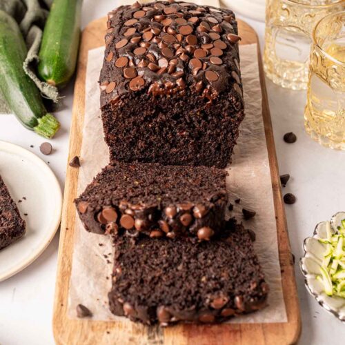 Chocolate zucchini bread with lots of chocolate chips on top and a rich fluffy texture. Bread has two slices cut off.