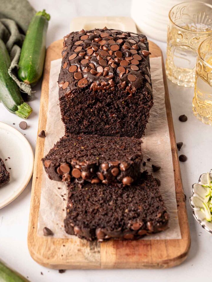 Chocolate zucchini bread with lots of chocolate chips on top and a rich fluffy texture. Bread has two slices cut off.
